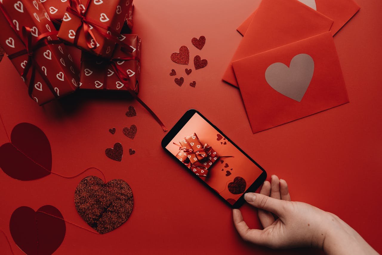 Mobile displaying digital Valentine wishes, surrounded by hearts and greeting cards for Valentine's Day on a red background.