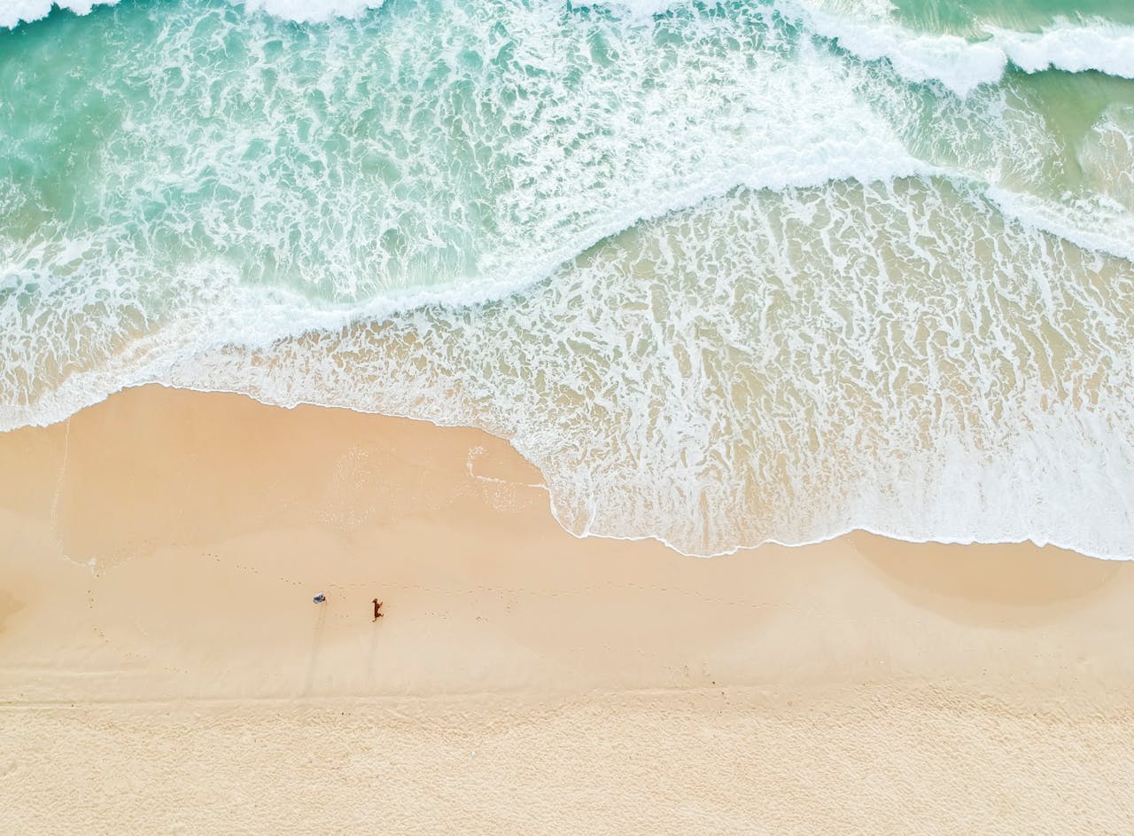 A breathtaking aerial view of a pristine beach vacation spot with clean aqua-green water, soft golden sand.