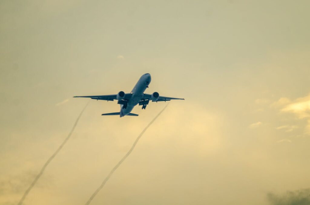 Airplane flying in the evening sky with a colorful sunset in the background.