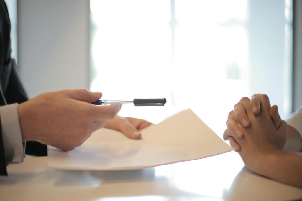 A hand holding a pen and paper symbolizing reviewing an geoblue travel insurance policy.