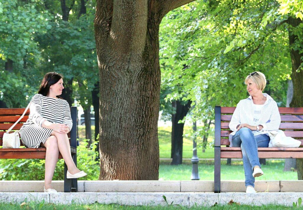 Women sitting in a park, engaging in a friendly conversation with each other.