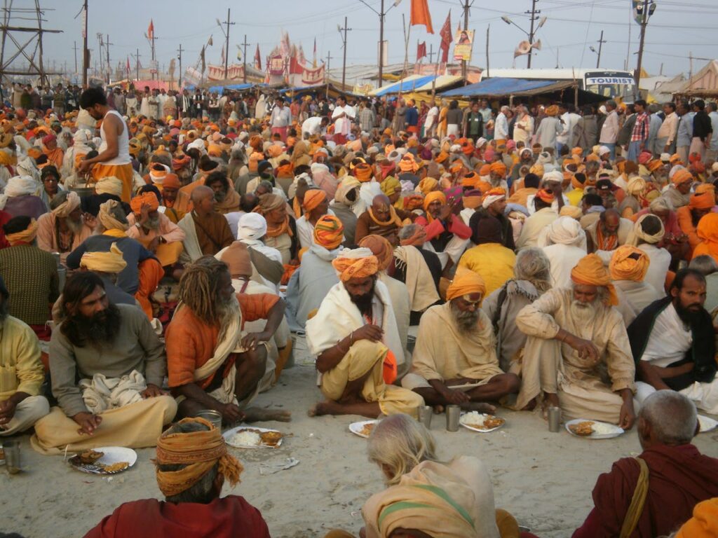 Thousands of sadhus sitting on the floor, having food at a large gathering during Kumbh Mela.