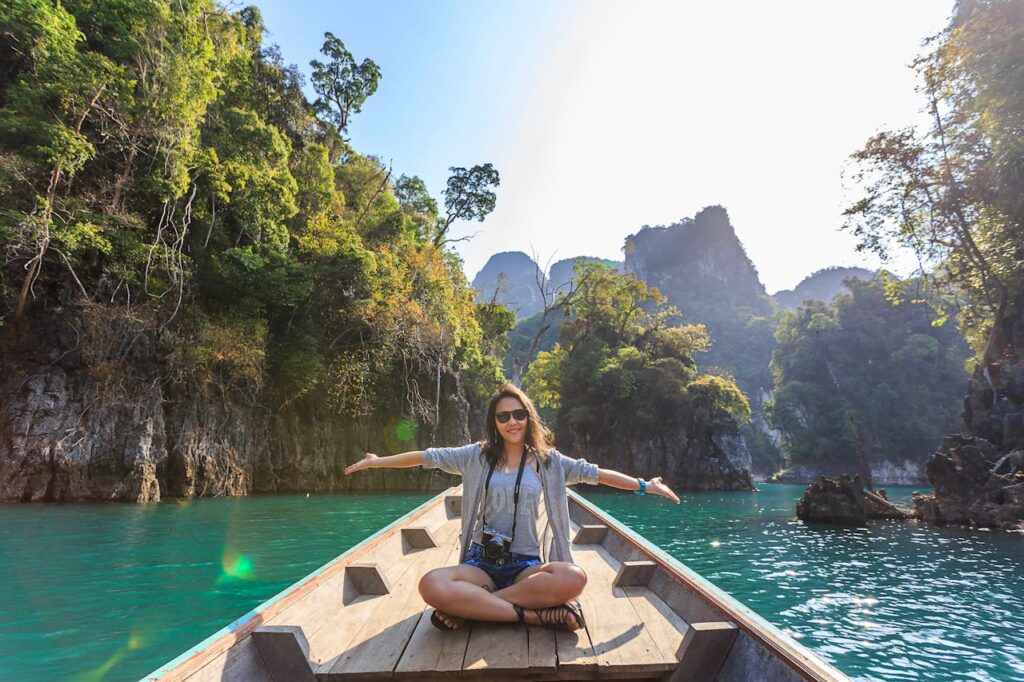 Woman sitting on a boat smiling with a beautiful view of the sea and mountains in the background.