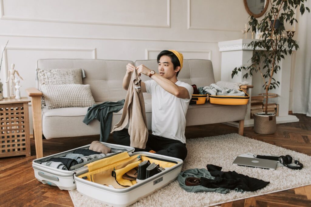 Man packing his baggage while sitting on the floor, planning for a vacation with smart packing techniques.