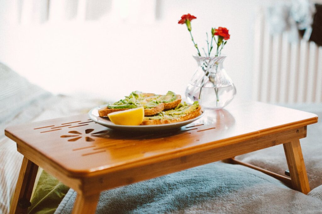 A beautifully arranged breakfast-in-bed featuring avocado toast, fresh fruits, and a flower vase—an elegant choice for custom Valentine’s Day gifts to start Valentine’s Day 2025 with love and warmth.