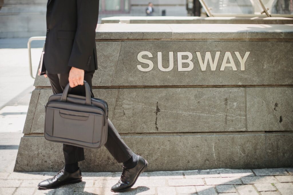 A professional man walking with a briefcase near a subway station, exuding confidence and business travel readiness.