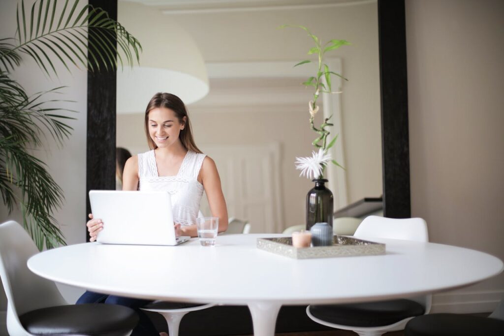 A professional woman working on her laptop in a hotel room workspace, managing tasks efficiently during business travel.