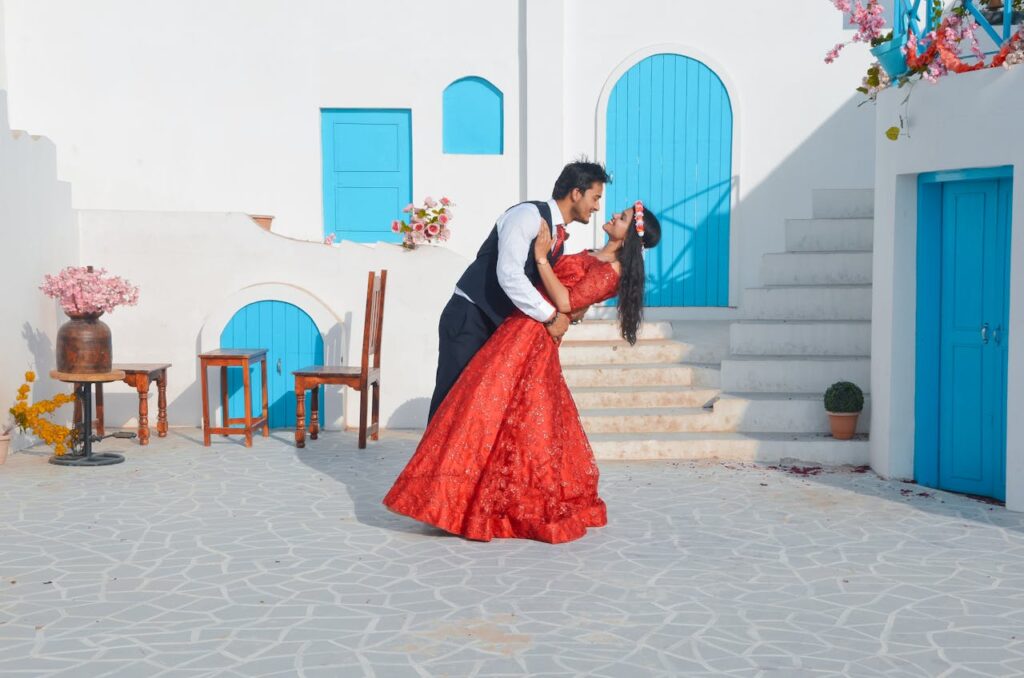 A romantic couple enjoys a quiet moment in Santorini, Greece, with iconic white walls and blue windows in the background, celebrating Valentine’s Day 2025 on a luxurious romantic escape.