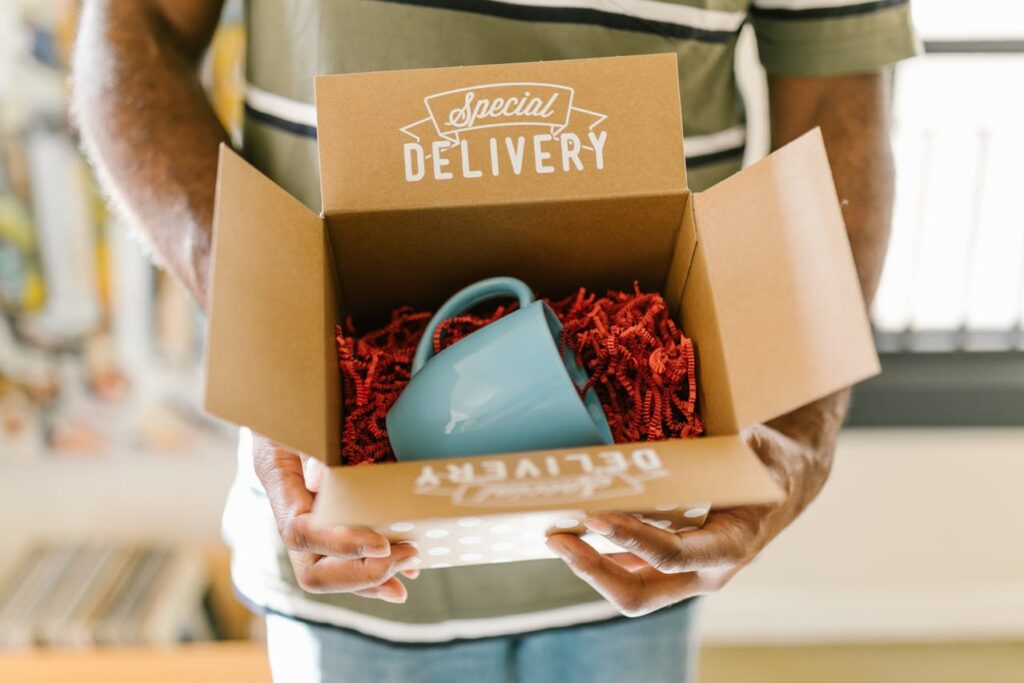 Hands holding a gift box with an aqua cup inside, symbolizing a heartfelt Valentine's Day surprise for a digital nomad from a loved one far away.