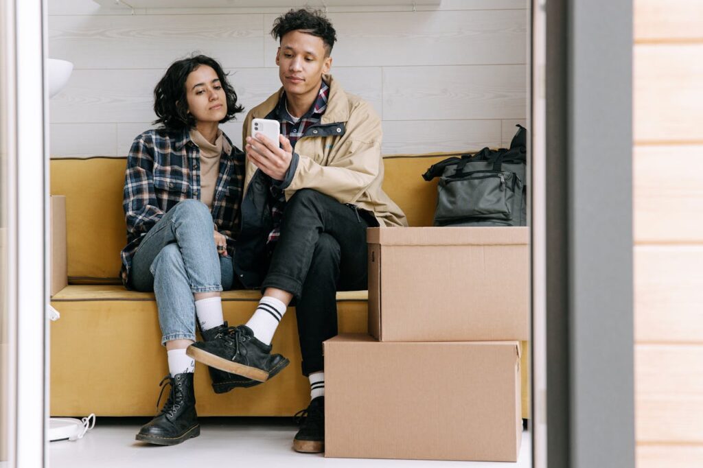 Airbnb hosts managing their listings on a cellphone while sitting together and planning to expand their Airbnb portfolio—an important step in how to become an Airbnb host.
