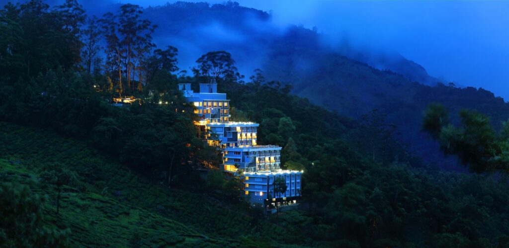 Chandy's Windy Woods Resort in Munnar during the evening, surrounded by fog and lush green trees in the mountain landscape.