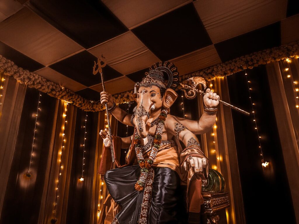 Ganesh idol with yellow lights and drapes creating festive Ganapati decoration at home