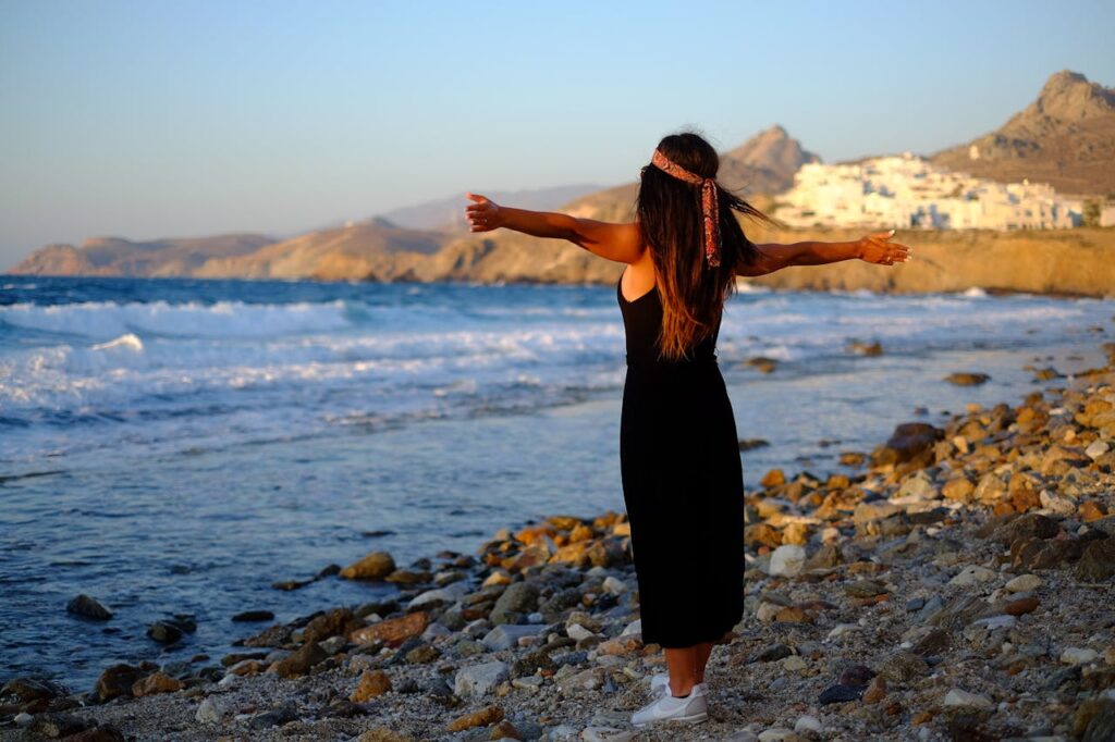 Woman in a black long sleeveless dress walking through Naxos, a serene stop on any Greece travel itinerary.