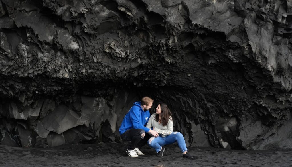 Couple enjoying their vacation on Reynisfjara Black Sand Beach, a must-see stop on an Iceland travel itinerary.