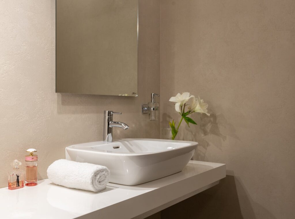 White flower decoration at home in a transparent vase placed in a washroom beside toiletries.