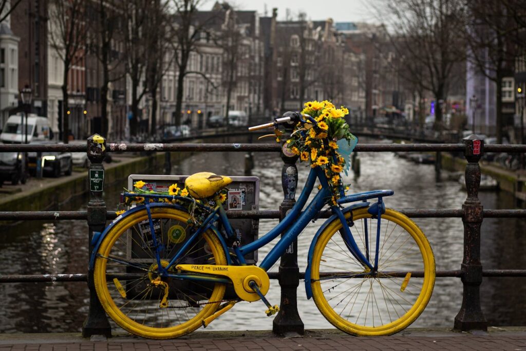 Colorful blue and yellow bicycle parked beside an Amsterdam canal, perfect for a Europe travel itinerary