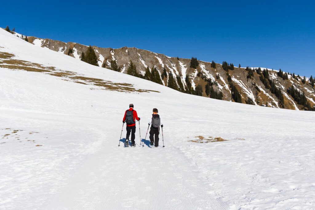 Hikers on snowy trails in the Swiss Alps with panoramic mountain views, ideal for a Switzerland travel itinerary.