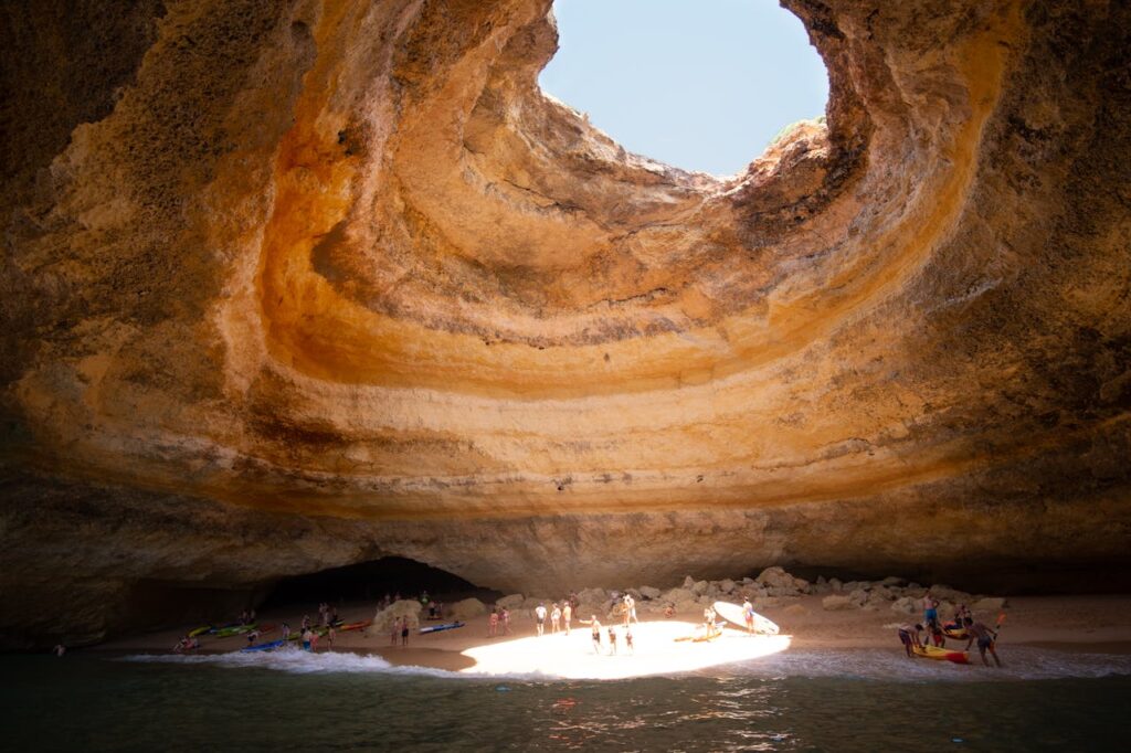 People exploring a sea cave with an open skylight in Albufeira, part of a scenic Portugal travel itinerary.