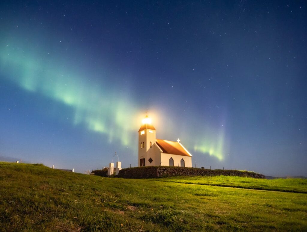 Northern Lights glowing above a house in Iceland, a magical experience in an Iceland travel itinerary.