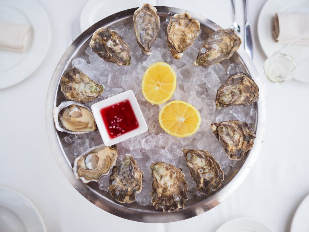 Fresh mussels with lemon and sauce served on ice at a seaside restaurant in Portugal, highlighting local cuisine on a Portugal travel itinerary.