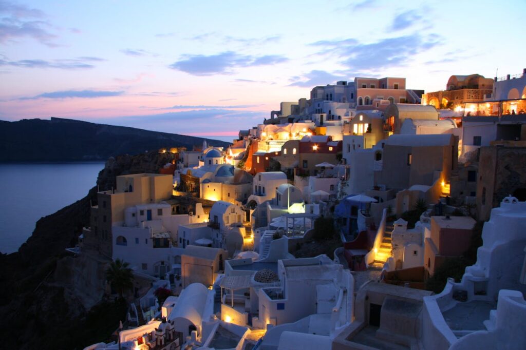 Whitewashed cliffside buildings in Santorini, Greece at sunset, a highlight of your Greece travel itinerary