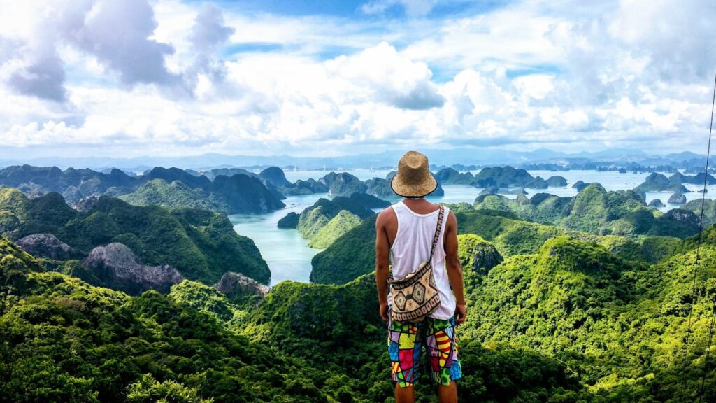 A tourist standing on a cliff enjoying panoramic mountain views in Vietnam, representing a highlight of the Vietnam travel itinerary.