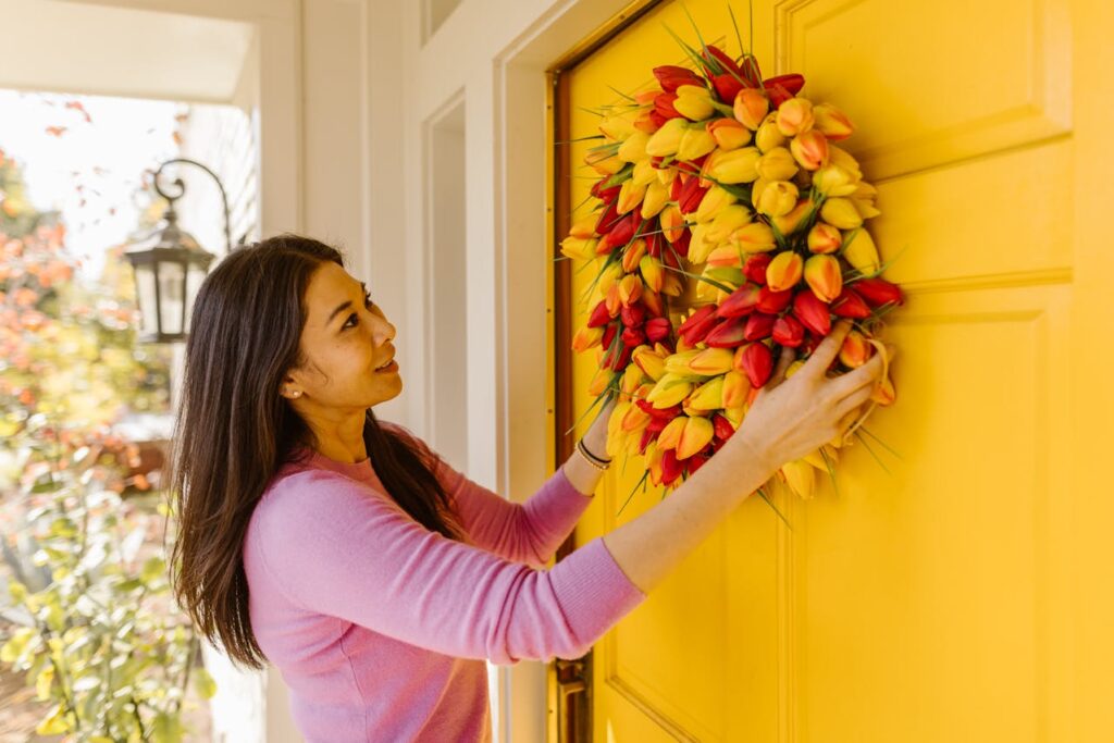 A woman doing flower decoration at home, arranging fresh flowers at her front door entrance.