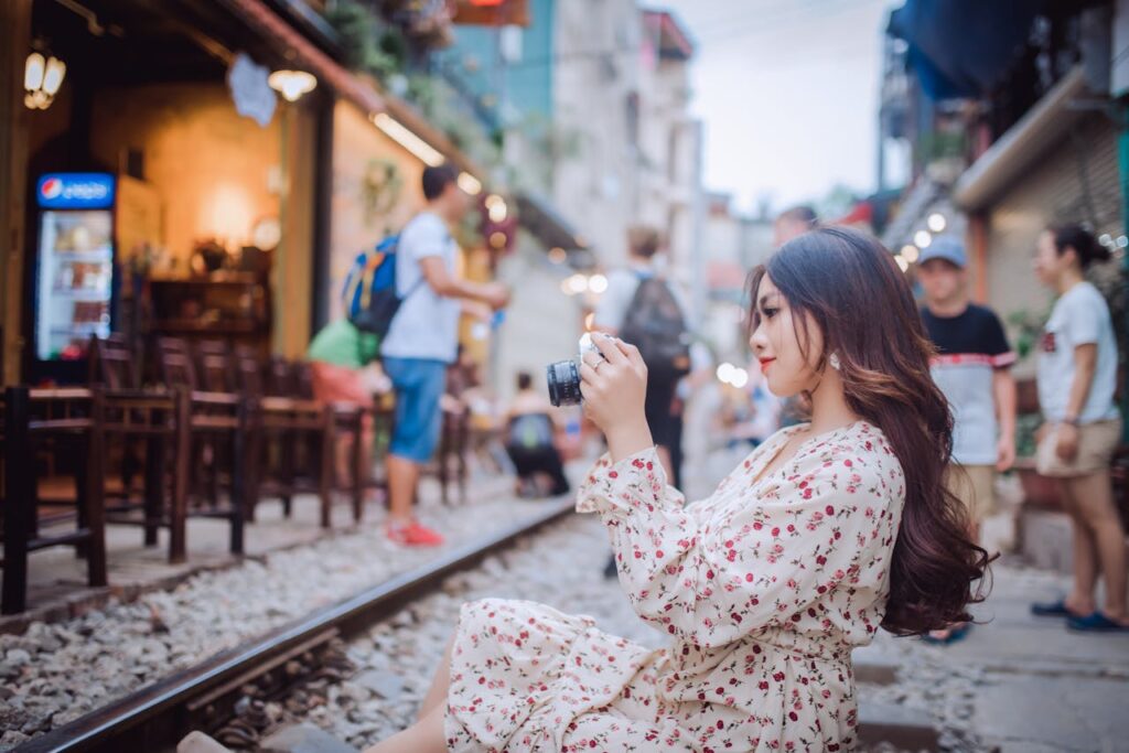 A woman capturing a vibrant street scene with her camera during her Vietnam travel itinerary.