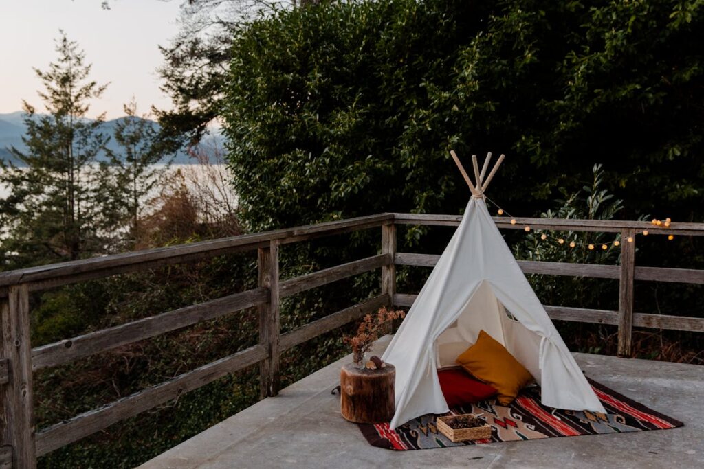 Romantic camp setup with cushions and lights for cozy anniversary decoration at home.