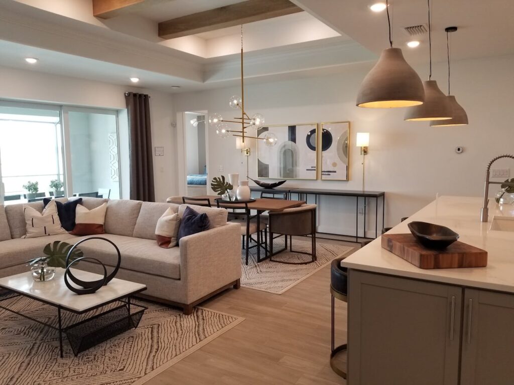 A warm-tone living area with a stylish couch, plush cushions, soft carpet, elegant ceiling lights, and an adjoining dining space, styled with Westside Home Decor.