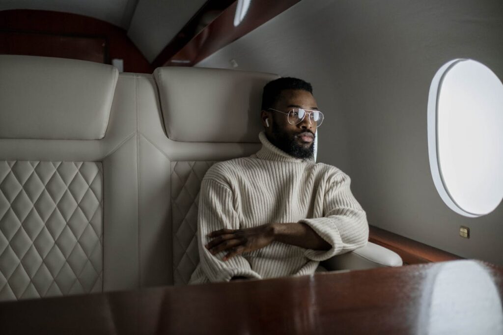 Business traveler in business class using premium facilities with American Express card, highlighting American Express Global Business Travel Benefits for luxury and comfort.