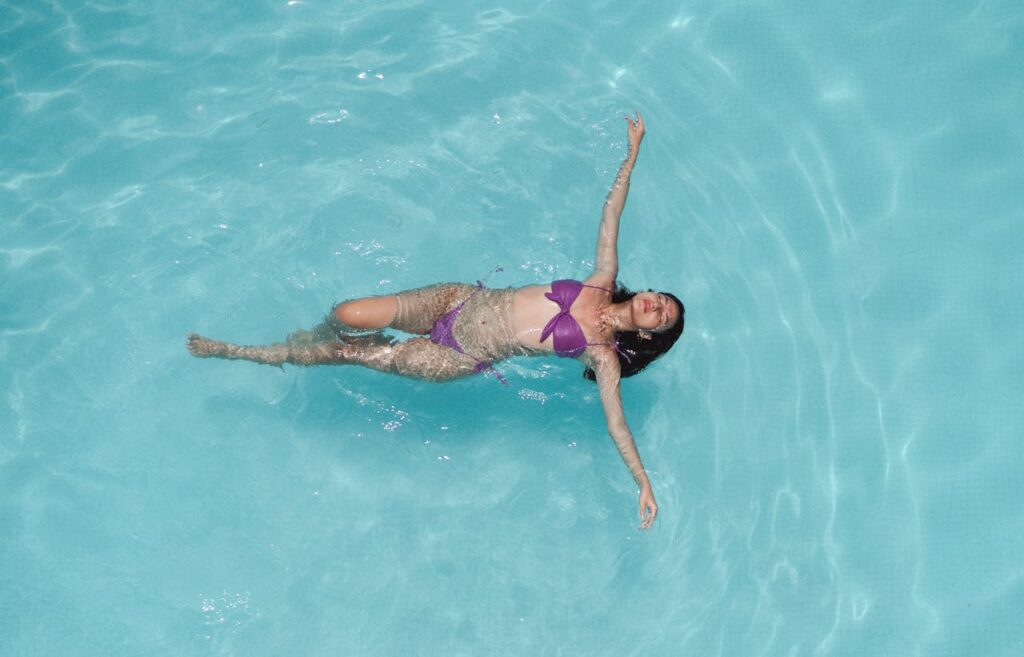 Woman swimming in a bikini at a resort pool with safe and treated water, reducing risks of brain eating amoeba.