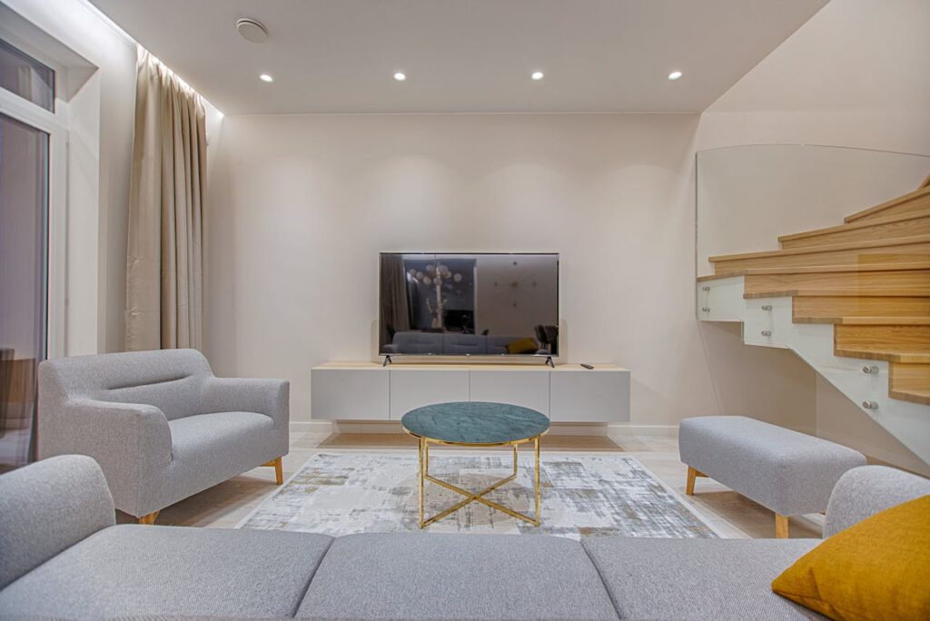 Modern living room setup showcasing essential airbnb amenities with light grey cozy sofas and smart tv.